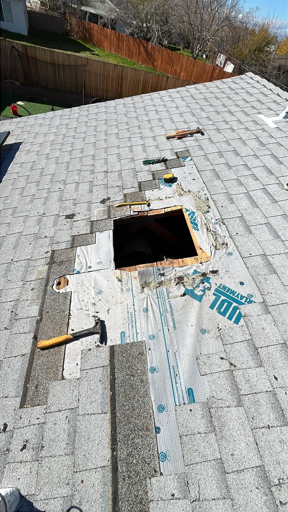 Roof opened for storm damage repair with tools on shingles